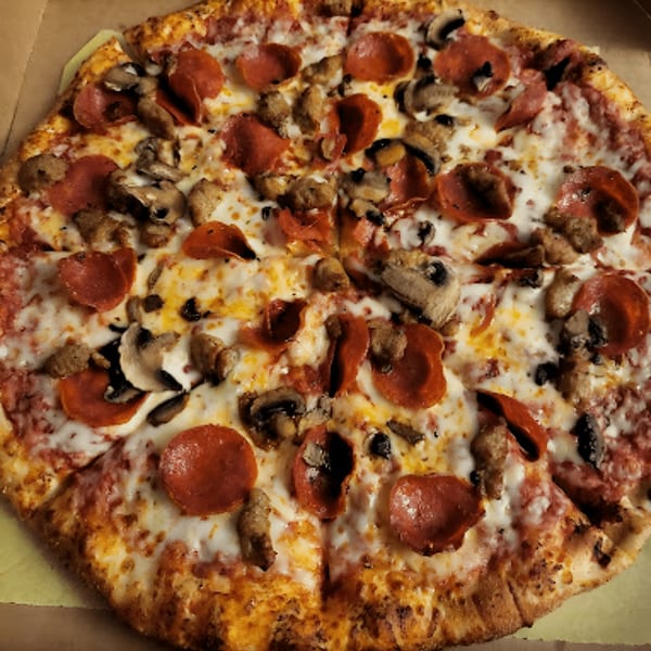Amelio's Pizza with pepperoni, sausage, and mushrooms, sliced and ready to eat.