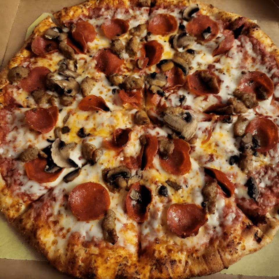 Amelio's Pizza with pepperoni, sausage, and mushrooms, sliced and ready to eat.