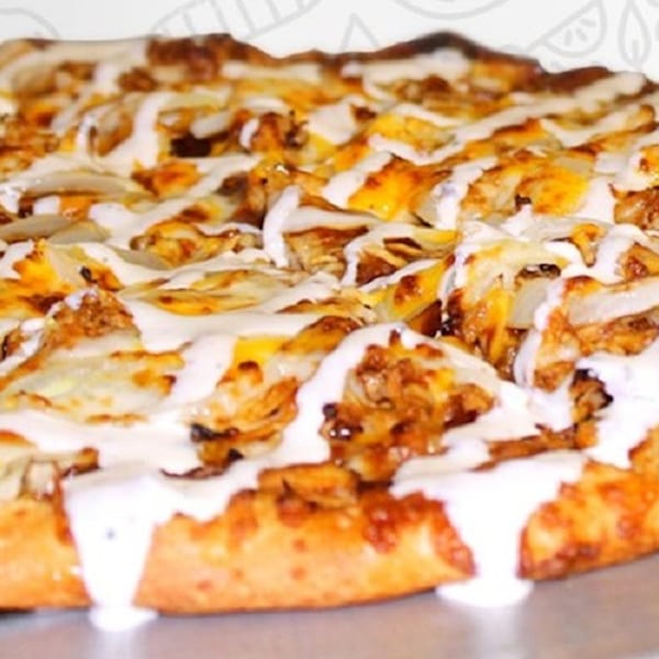 Close-up of a Buffalo chicken pizza from Amelio's Pizza and More, drizzled with white sauce.