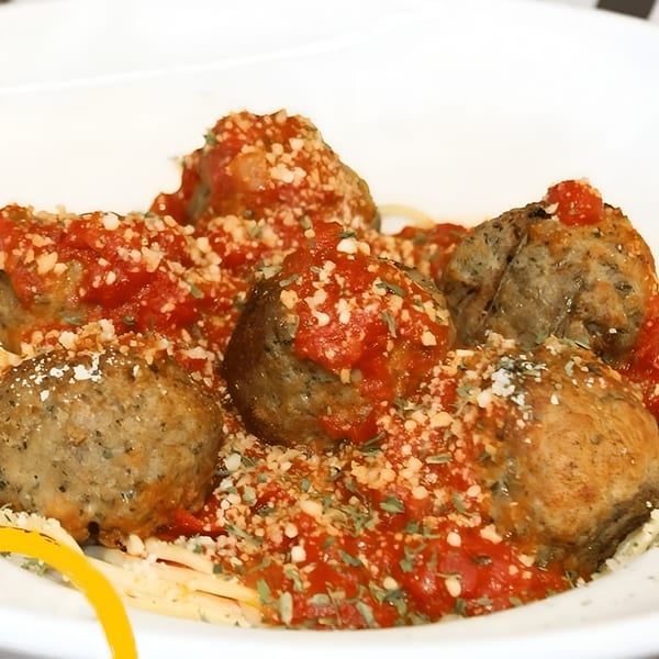 Close-up of Amelio's meatballs covered in red sauce, parmesan cheese, and herbs.